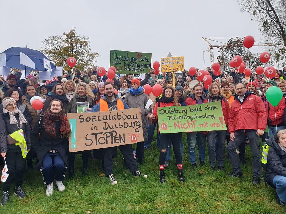 Mitarbeiter*innen des DRK Duisburg halten Plakate für die Demonstration hoch