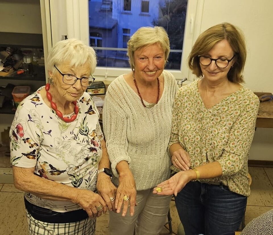 Präsentation der Schmuckstücke Kursleitung und zwei Teilnehmerinnen zeigen Ihren selbst erstellten Schmuck