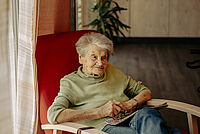 Ältere Dame sitzt im Sessel